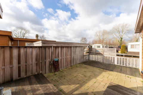 Cour clôturée avec terrasse en bois au Luxury chalet 54 Bantega, une péniche aux Pays-Bas, ciel nuageux.