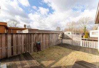 Cortile recintato con decking in legno al Luxury chalet 54 Bantega houseboat nei Paesi Bassi, cielo nuvoloso.