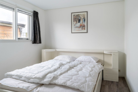 Chambre avec lit double, draps blancs et fenêtre dans le houseboat Luxury chalet «54 Bantega» aux Pays-Bas.
