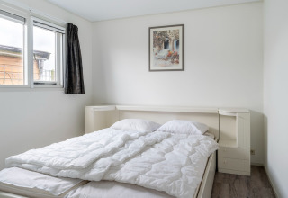 Chambre avec lit double, draps blancs et fenêtre dans le houseboat Luxury chalet «54 Bantega» aux Pays-Bas.
