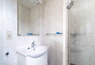 Moderne badkamer met wastafel, spiegel en douche op woonboot Luxury chalet «54 Bantega» in Nederland.