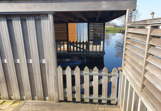 Houten poortje en hek aan de drijvende terras van het Luxury chalet «54 Bantega» woonboot in Nederland.