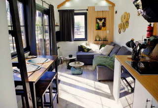 Lichte, gezellige leefruimte met eettafel en bank in het Charming Tiny House in Nederland.