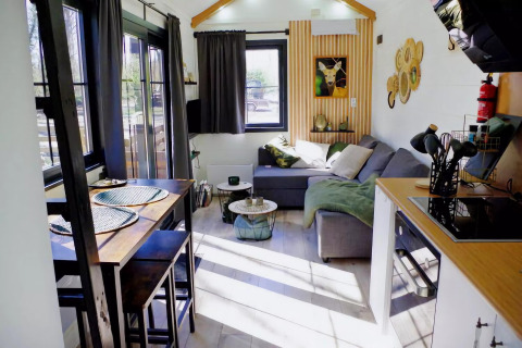 Acogedora sala de estar luminosa con mesa de comedor y sofá en Charming Tiny House, Países Bajos.