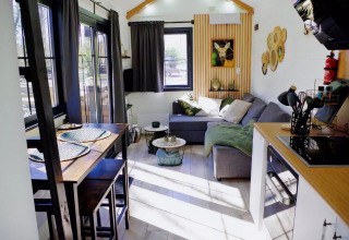 Acogedora sala de estar luminosa con mesa de comedor y sofá en Charming Tiny House, Países Bajos.
