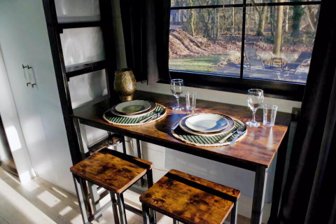 Pequeño comedor acogedor en Charming Tiny House, Países Bajos, con mesa para dos junto a la ventana.