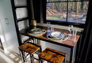 Pequeño comedor acogedor en Charming Tiny House, Países Bajos, con mesa para dos junto a la ventana.