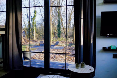 Vista del patio y bosque invernal a través de grandes ventanales en Charming Tiny House, Países Bajos.