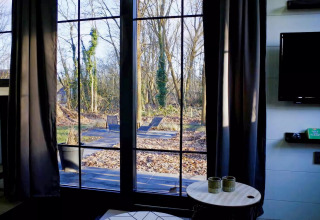 Vista del patio y bosque invernal a través de grandes ventanales en Charming Tiny House, Países Bajos.