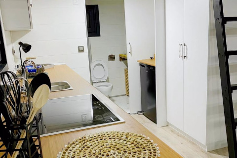Cocina pequeña y moderna en una tiny house con acceso al baño y escalera a un altillo en los Países Bajos.
