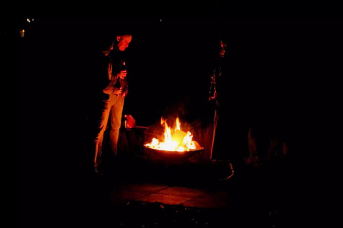 Dos personas disfrutan de una fogata nocturna frente a la Charming Tiny House en los Países Bajos.
