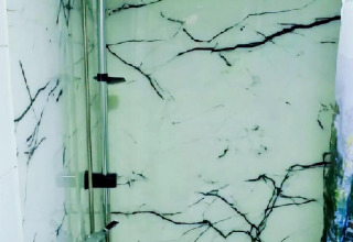 Pared de ducha con diseño de mármol en Charming Tiny House, Países Bajos, con vidrio y vetas oscuras.