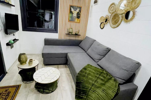 Salón moderno en el Charming Tiny House en Países Bajos con sofá gris y decoración acogedora.