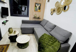 Salón moderno en el Charming Tiny House en Países Bajos con sofá gris y decoración acogedora.