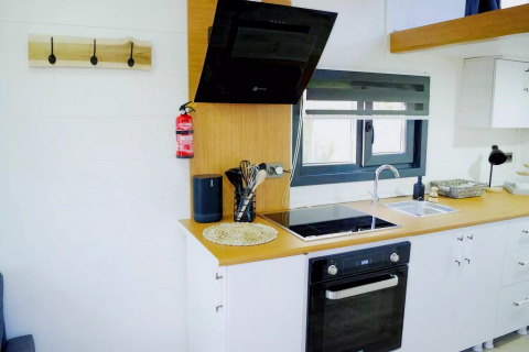 Cocina moderna en Charming Tiny House, Países Bajos, con campana negra, horno y gran ventana.