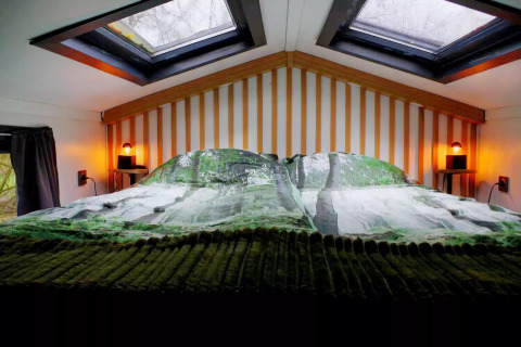 Acogedor altillo de dormitorio en el Charming Tiny House en Países Bajos, con claraboyas y luces tenues.
