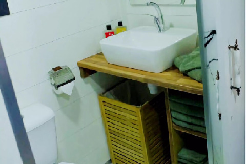 Baño compacto y moderno de una tiny house en los Países Bajos con lavabo y toallas verdes dobladas.