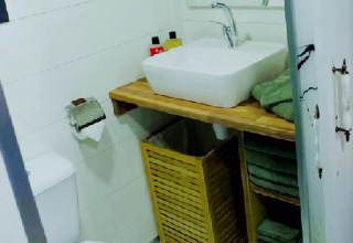 Baño compacto y moderno de una tiny house en los Países Bajos con lavabo y toallas verdes dobladas.