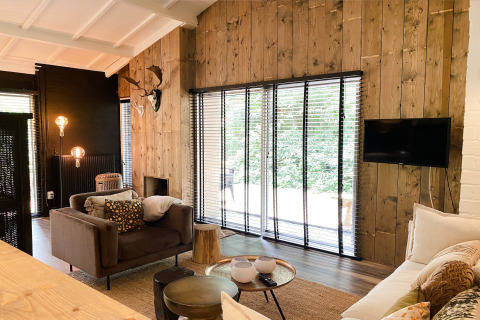 Stijlvolle woonkamer in Dutch Cabin Houses C66 in Nederland met houten muren, grote ramen en gezellige inrichting.