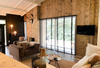 Stijlvolle woonkamer in Dutch Cabin Houses C66 in Nederland met houten muren, grote ramen en gezellige inrichting.