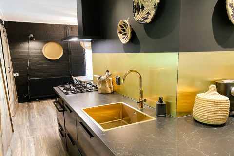 Moderne keuken in Dutch Cabin Houses C66, Nederland, met zwart-gouden accenten en gevlochten manden.