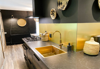 Moderne keuken in Dutch Cabin Houses C66, Nederland, met zwart-gouden accenten en gevlochten manden.
