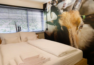 Slaapkamer in Dutch Cabin Houses C66 in Nederland met wit beddengoed en grote geitenmuurprint.
