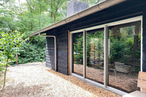 Moderne houten lodge Dutch Cabin Houses C66 in Nederland met grote ramen en groene omgeving.