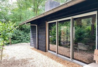 Moderne houten lodge Dutch Cabin Houses C66 in Nederland met grote ramen en groene omgeving.