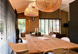 Moderne eetruimte met houten wanden, grote ramen en rotan lampen in Dutch Cabin Houses C66, Nederland.