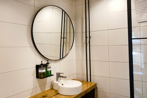 Moderne badkamer met ronde spiegel en houten wastafel bij Dutch Cabin Houses C66 in Nederland.