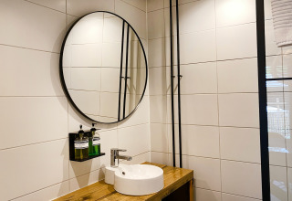 Moderne badkamer met ronde spiegel en houten wastafel bij Dutch Cabin Houses C66 in Nederland.