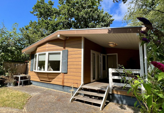 Buitenzicht op een klein familiechalet genaamd Small family chalet close to beach, omringd door groen.