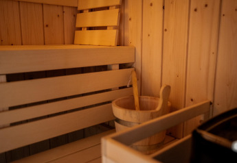 Innenansicht einer Holzsauna mit Bank, Kelle und Eimer im Ferienhaus in Haarle nahe Sallandse Heuvelrug, Niederlande.