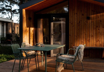 Gemütlicher Außenbereich mit Tisch und grünen Stühlen vor einem Holzhaus im Ferienhaus in Haarle.
