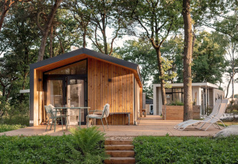 Chalet de vacances en bois à Haarle près de Sallandse Heuvelrug, avec terrasse et fauteuils de jardin.