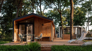 Cabaña de vacaciones de madera en Haarle cerca de Sallandse Heuvelrug, con terraza y sillas exteriores.