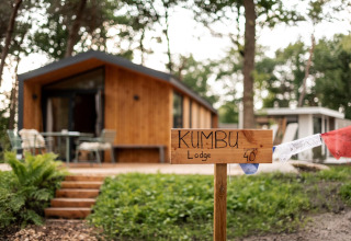 Træhytte med skilte, hvor der står 'Kumbu Lodge', omgivet af træer nær Sallandse Heuvelrug i Holland.
