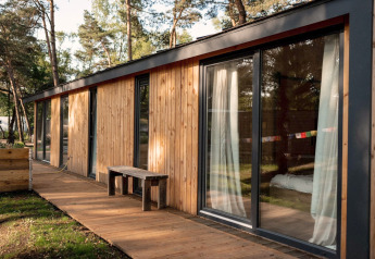 Vue extérieure d'une maison de vacances en bois avec grandes fenêtres près de Sallandse Heuvelrug, Pays-Bas.