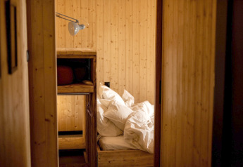 Holzvertäfeltes Schlafzimmer mit Etagenbett und unordentlicher Bettwäsche in einem Ferienhaus bei Sallandse Heuvelrug.
