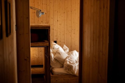 Træbeklædt soveværelse med køjeseng og rodet sengetøj på Holiday home i Haarle nær Sallandse Heuvelrug.