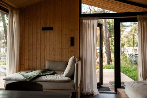 Indvendig udsigt over feriehus i Haarle nær Sallandse Heuvelrug, med sofa og åbne døre til naturen.