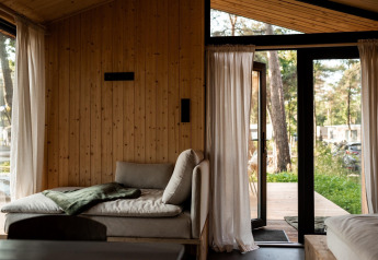 Vista interior de casa de vacaciones en Haarle cerca de Sallandse Heuvelrug, con sofá y puertas abiertas al jardín.