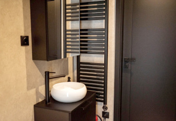 Salle de bain moderne avec robinet noir, vasque blanche et radiateur au Holiday home près de Sallandse Heuvelrug.