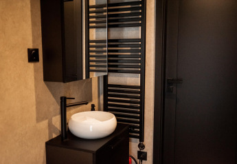 Moderne badkamer met zwarte kraan, waskom en handdoekradiator in een vakantiehuis nabij Sallandse Heuvelrug.