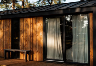 Houten vakantiehuis in Haarle bij Sallandse Heuvelrug, Nederland, met grote ramen en gordijnen.