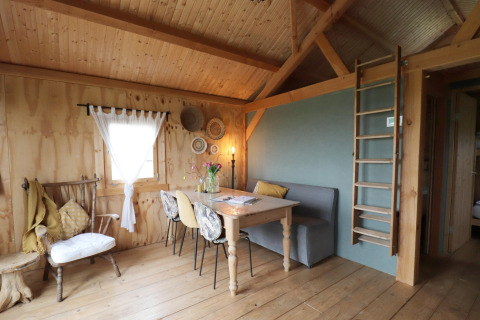 Knusse lodge met houten interieur, eethoek en ladder naar slaapzolder in Frisian Hideaway in Nederland.