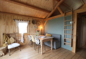 Knusse houten lodge met eetruimte en ladder naar de mezzanine in het Frisian Hideaway in Nederland.