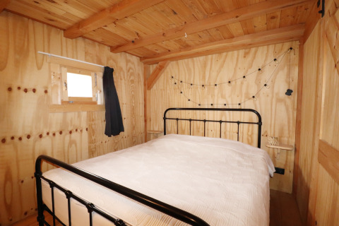 Sfeervolle slaapkamer met houten wanden, metalen bed en lichtsnoer in het Frisian Hideaway with Style in Nederland.
