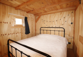 Knusse slaapkamer met houten wanden, ijzeren bed en sfeervolle lichtjes in Frisian Hideaway with Style in Nederland.